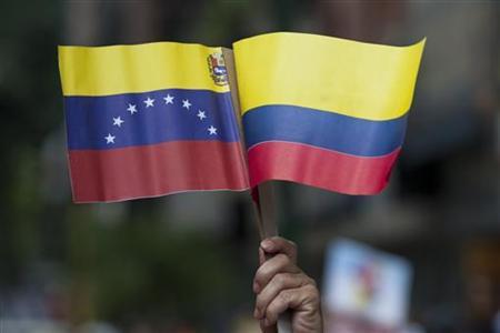 A supporter of Venezuelan President Hugo Chavez holds the flags of Colombia and Venezuela while taking part in a demonstration in support of peace in Colombia and the return to normal relations between the two nations in Caracas August 7, 2010. REUTERS/Carlos Garcia Rawlins